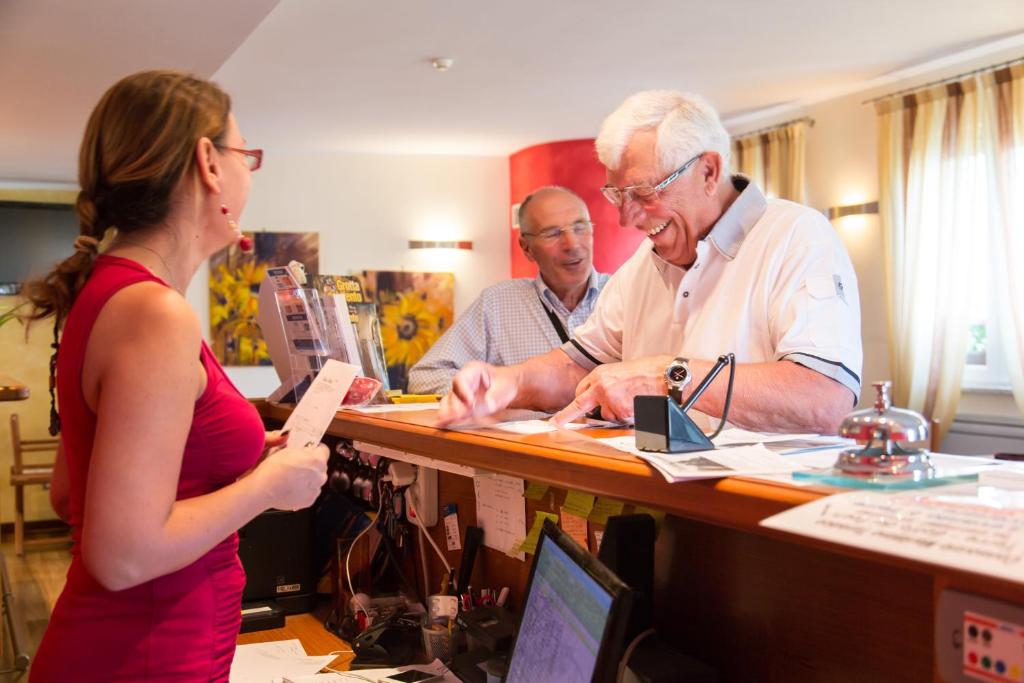 un homme et une femme debout à un bureau dans l'établissement Oasi Hotel, à Levanto