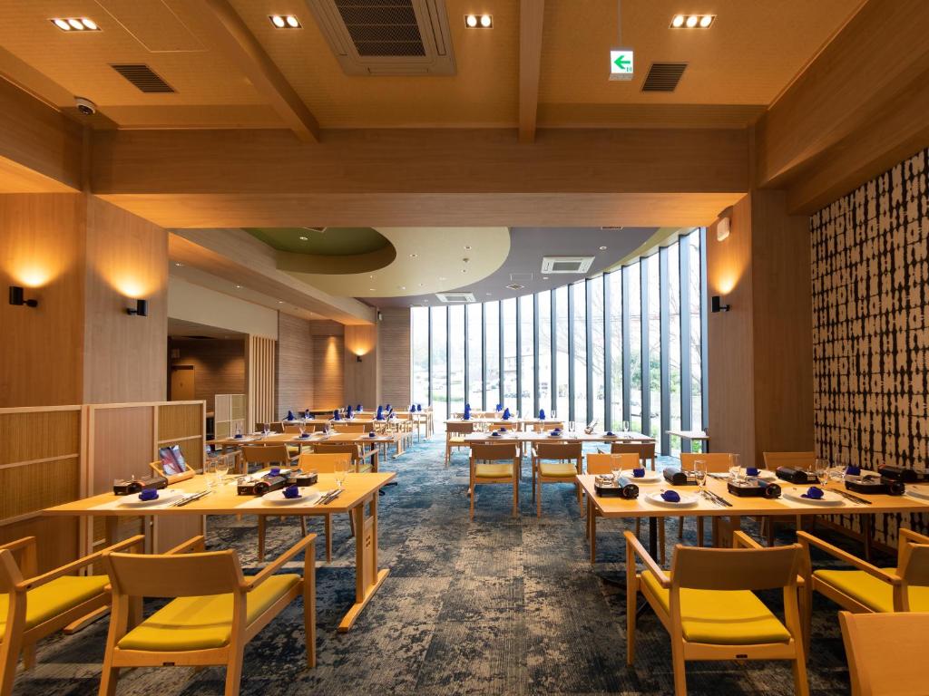 un restaurant avec des tables et des chaises et de grandes fenêtres dans l'établissement Akarinoyado Togetsu, à Beppu