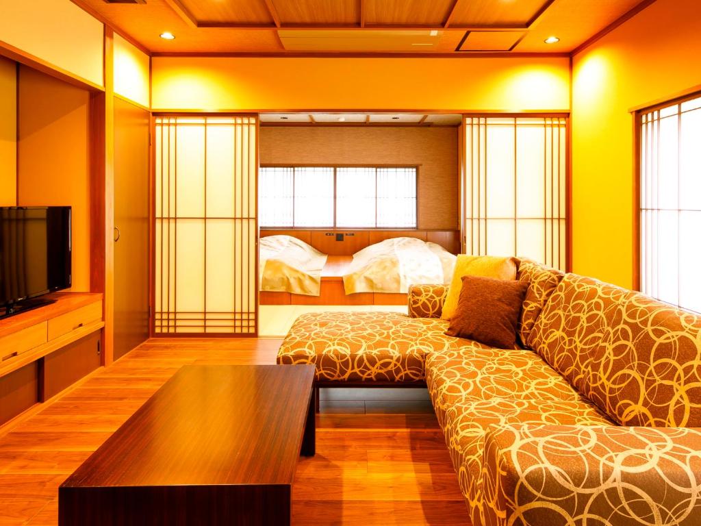 un salon avec un canapé et un lit dans l'établissement Kanazawa Yuwaku Onsen Kokarian, à Kanazawa