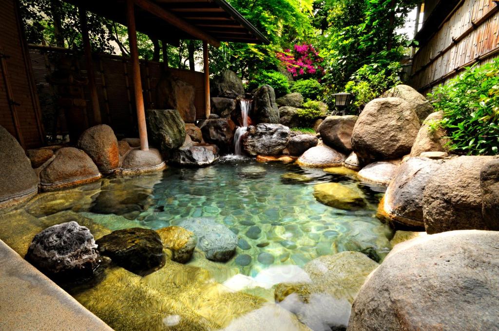 une piscine d'eau avec des rochers dans un jardin dans l'établissement Konya, à Matsue