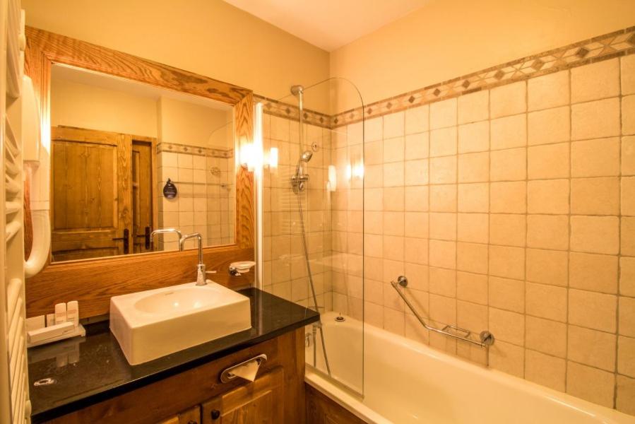 une salle de bain avec un lavabo, une baignoire et un miroir dans l'établissement Arc 1950 Chalet des lys, à Arc 1950