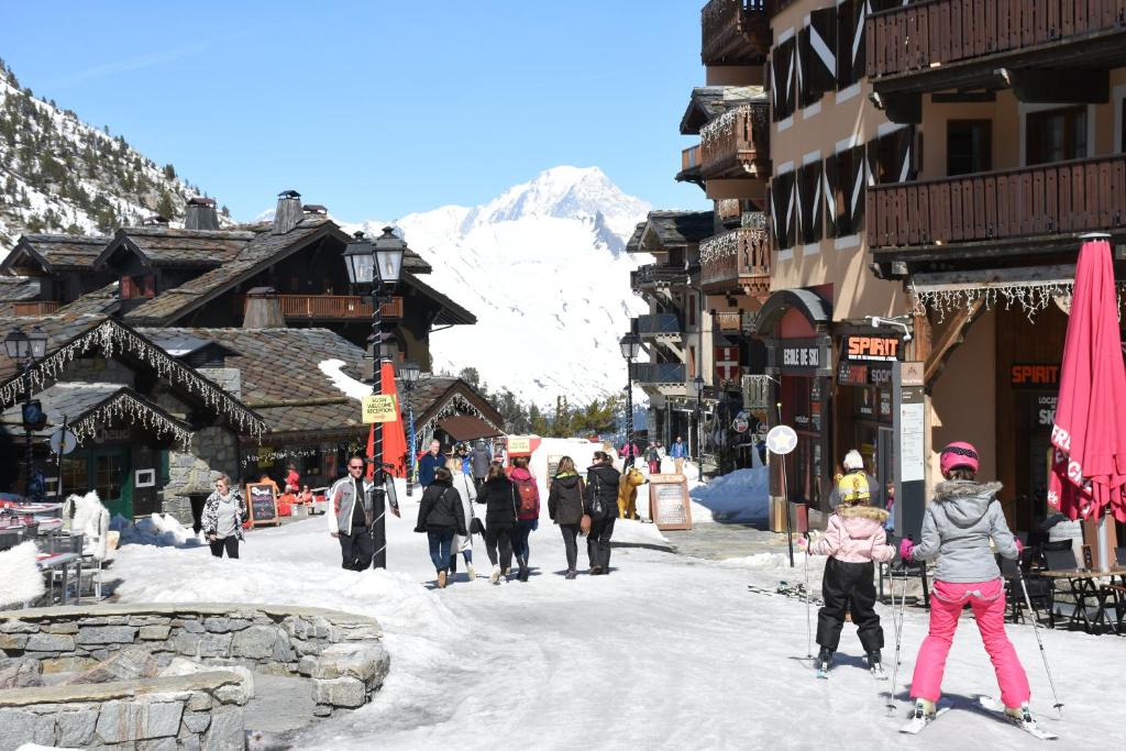 Un groupe de personnes marchant dans une rue enneigée dans l'établissement Arc 1950 Chalet des lys, à Arc 1950