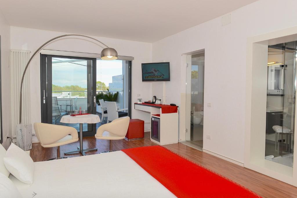 - une chambre avec un lit blanc, une table et des chaises dans l'établissement Stay Michelangelo Jesolo Only Adults, à Lido di Jesolo