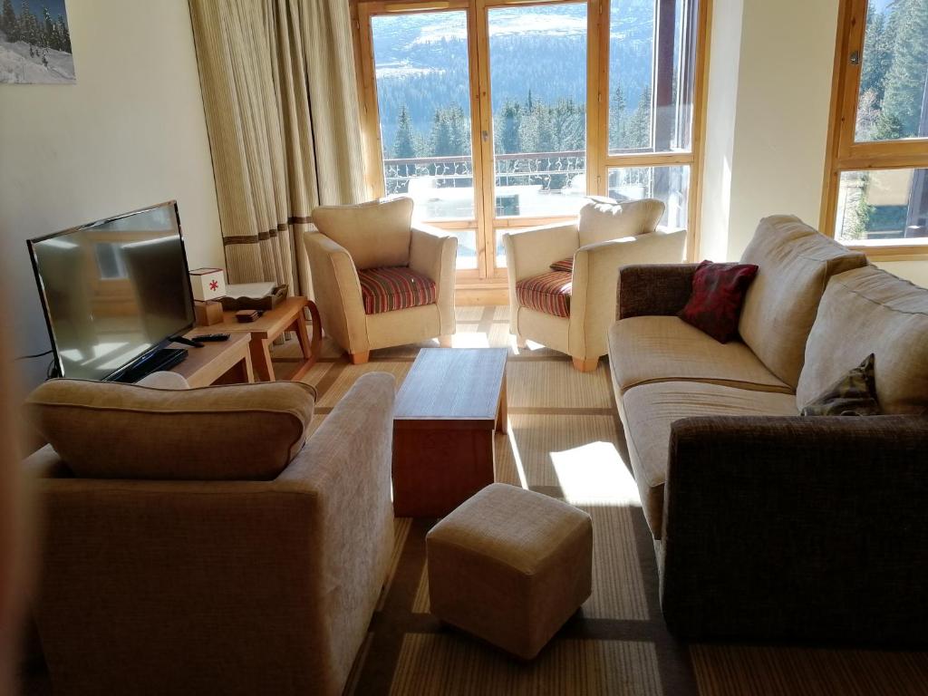 un salon avec des canapés et une télévision dans l'établissement Flaine prime ski in, ski out Apartment, à Flaine