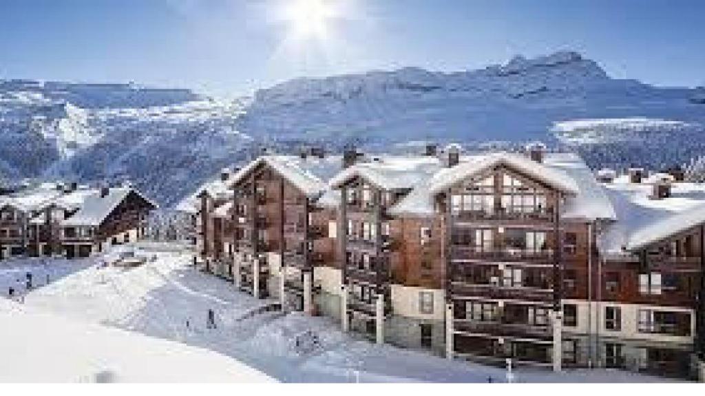 un groupe de bâtiments dans la neige avec des montagnes dans l'établissement Flaine prime ski in, ski out Apartment, à Flaine