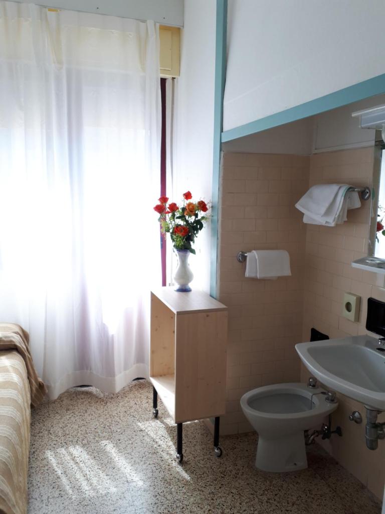 La salle de bains est pourvue de toilettes, d'un lavabo et d'un vase de fleurs. dans l'établissement Hotel Villa Dina, à Lido di Jesolo 197 autres photos