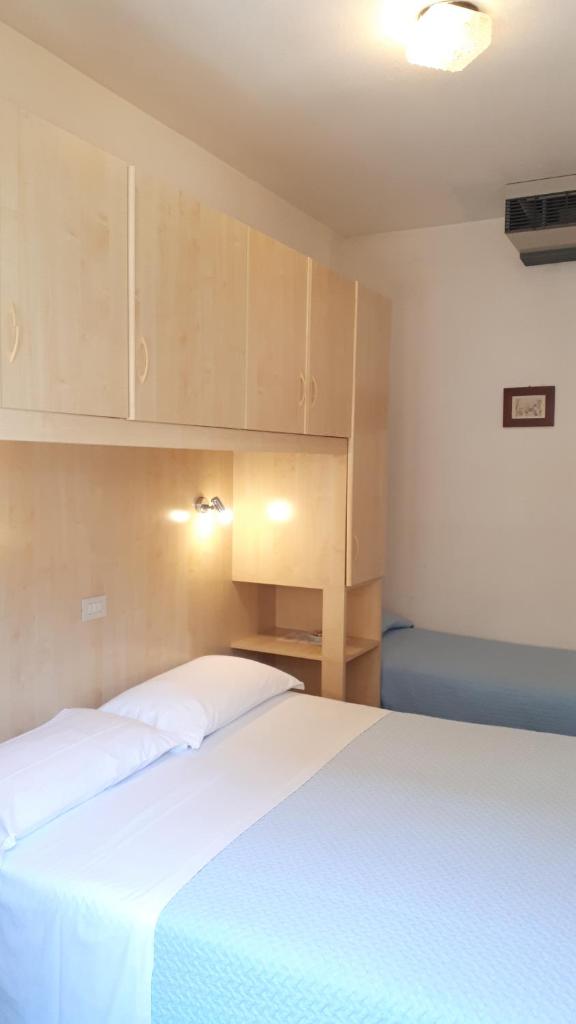 une chambre avec un lit avec des draps blancs et des armoires dans l'établissement Hotel Villa Dina, à Lido di Jesolo