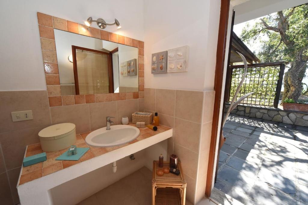 une salle de bain avec un lavabo et un miroir dans l'établissement Villa EnriMar, à Capoliveri