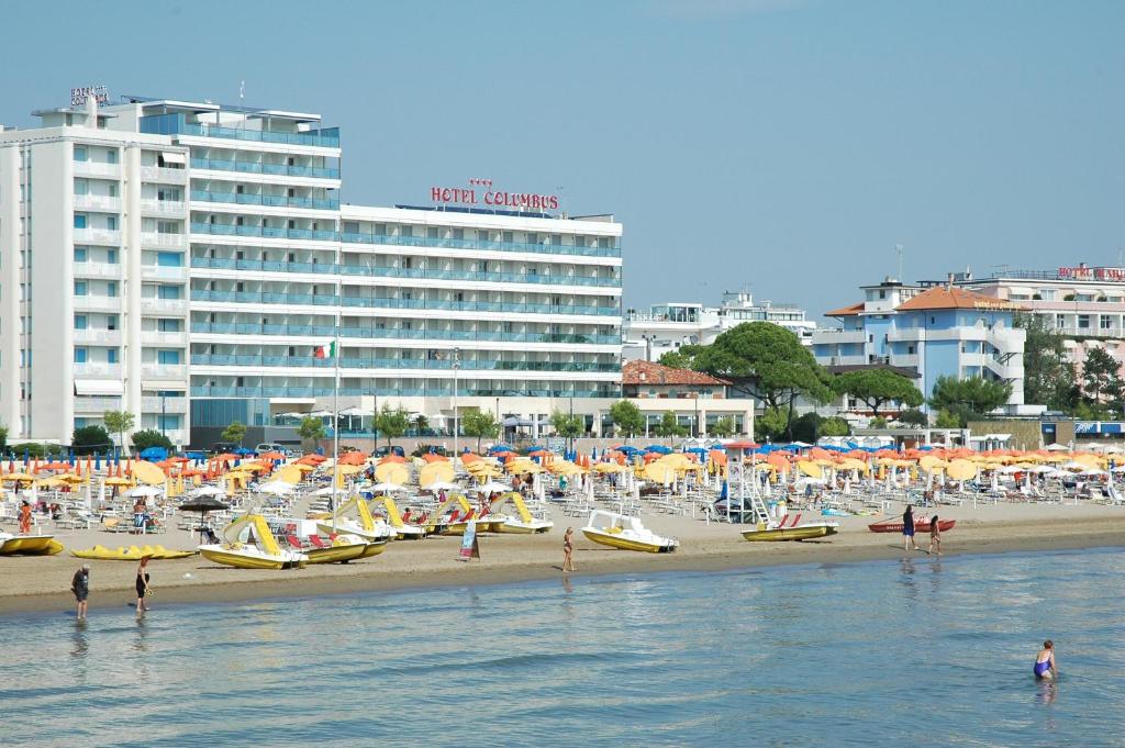 une plage avec des bateaux et des parasols et un hôtel dans l'établissement Hotel Columbus, à Lignano Sabbiadoro