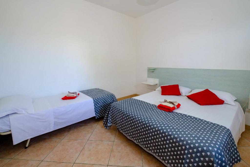 - 2 lits dans une chambre avec des oreillers rouges dans l'établissement Residenza Arene, à Gallipoli