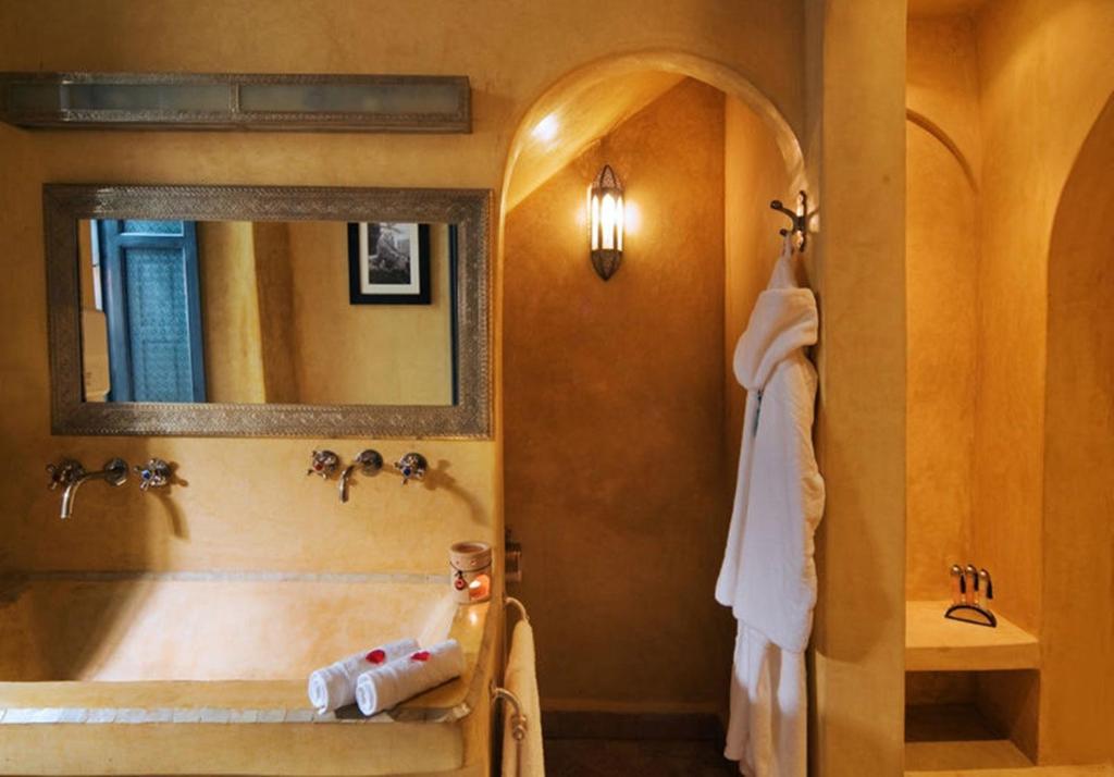 une salle de bain avec une baignoire, un lavabo et un miroir dans l'établissement Riad Cinnamon by Marrakech Riad, à Marrakech
