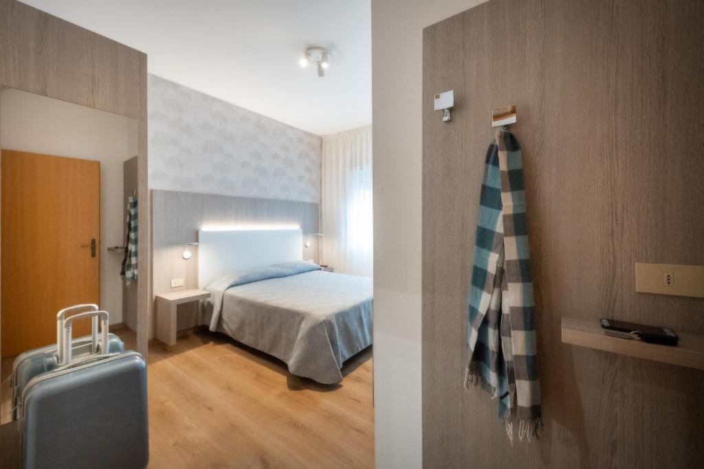 une chambre d'hôtel avec un lit et une valise dans l'établissement Hotel Fabris, à Caorle