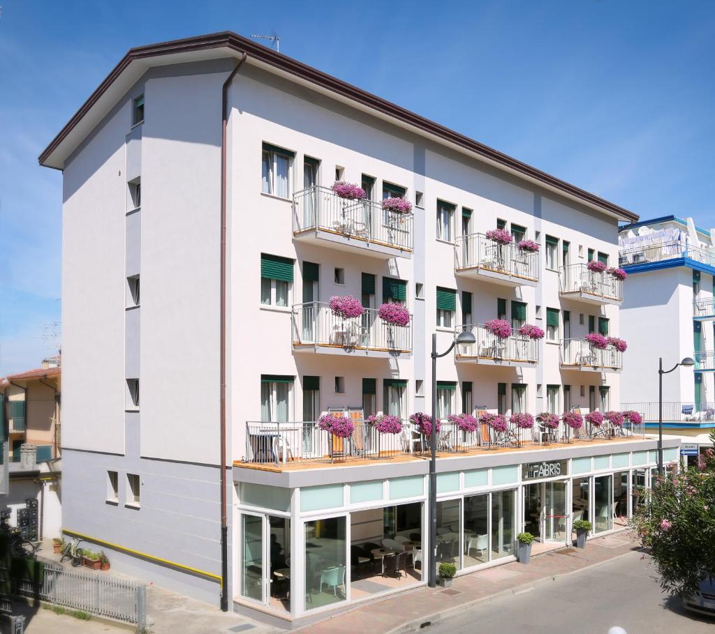 un bâtiment blanc avec des fleurs roses sur les balcons dans l'établissement Hotel Fabris, à Caorle