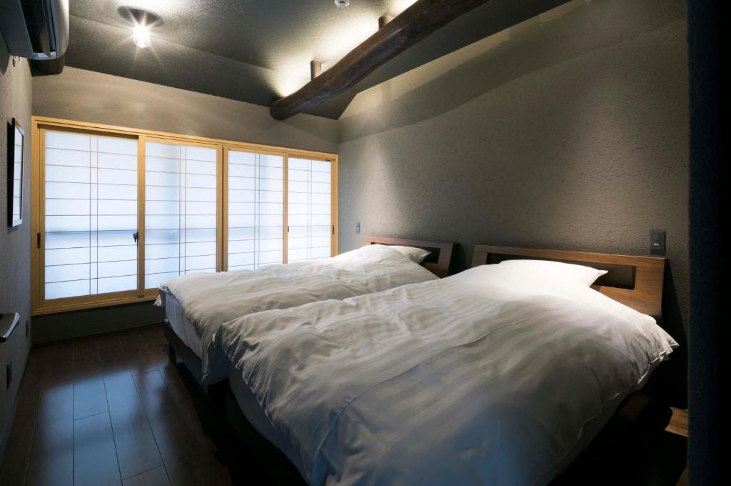 une chambre avec deux lits et une grande fenêtre dans l'établissement Arima Koyado Uraku, à Kobe