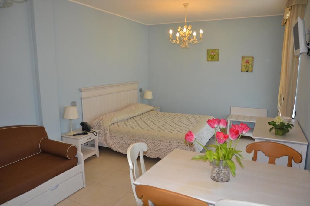 - une chambre avec un lit et une table fleurie dans l'établissement Incantea Resort, à Tortoreto Lido