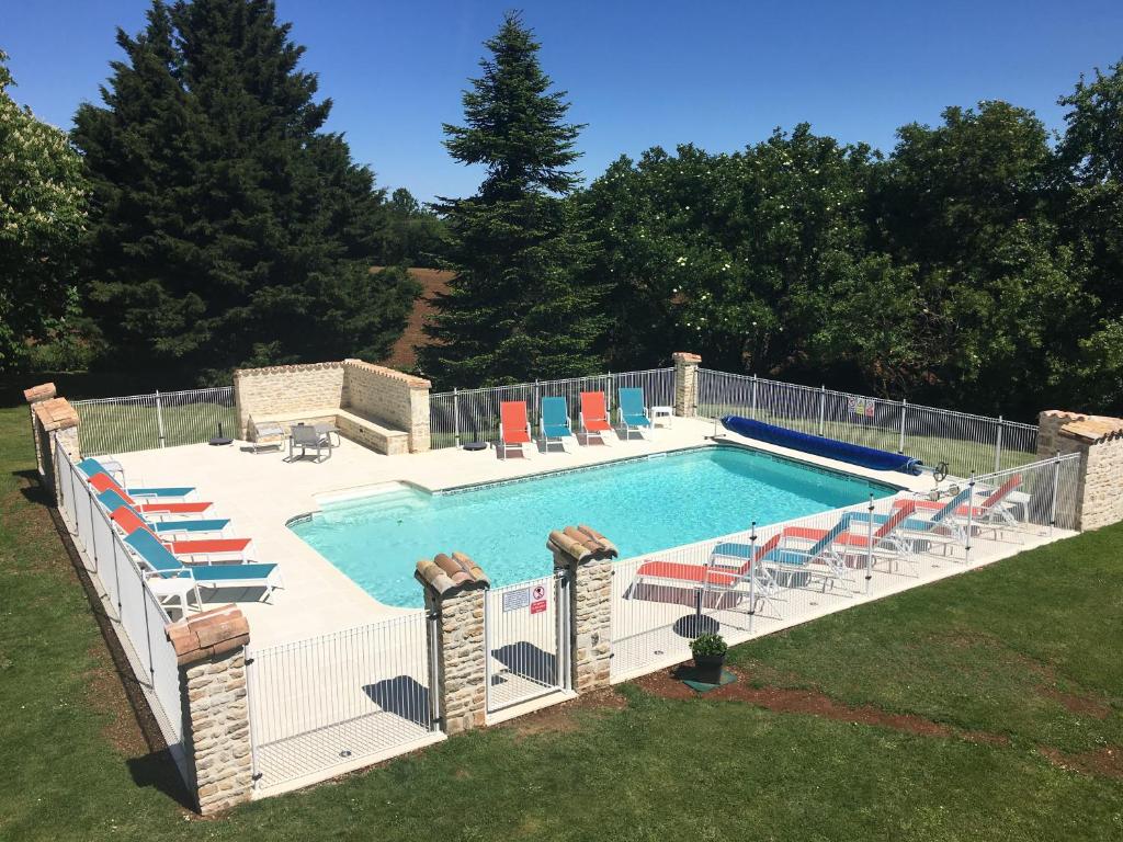 une grande piscine avec des chaises et une clôture dans l'établissement Gites dans les Champs, à Sauzé-Vaussais