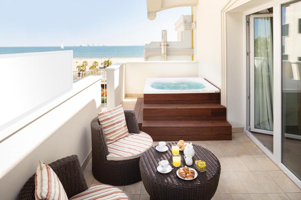 d'un balcon avec une table, des chaises et un bain à remous. dans l'établissement Hotel Ambassador, à Rimini