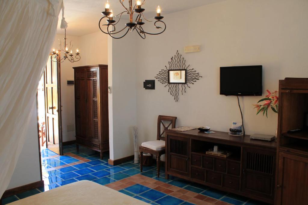 - une chambre avec un lit, une télévision et une commode dans l'établissement Luagos club Resort, à Lampedusa