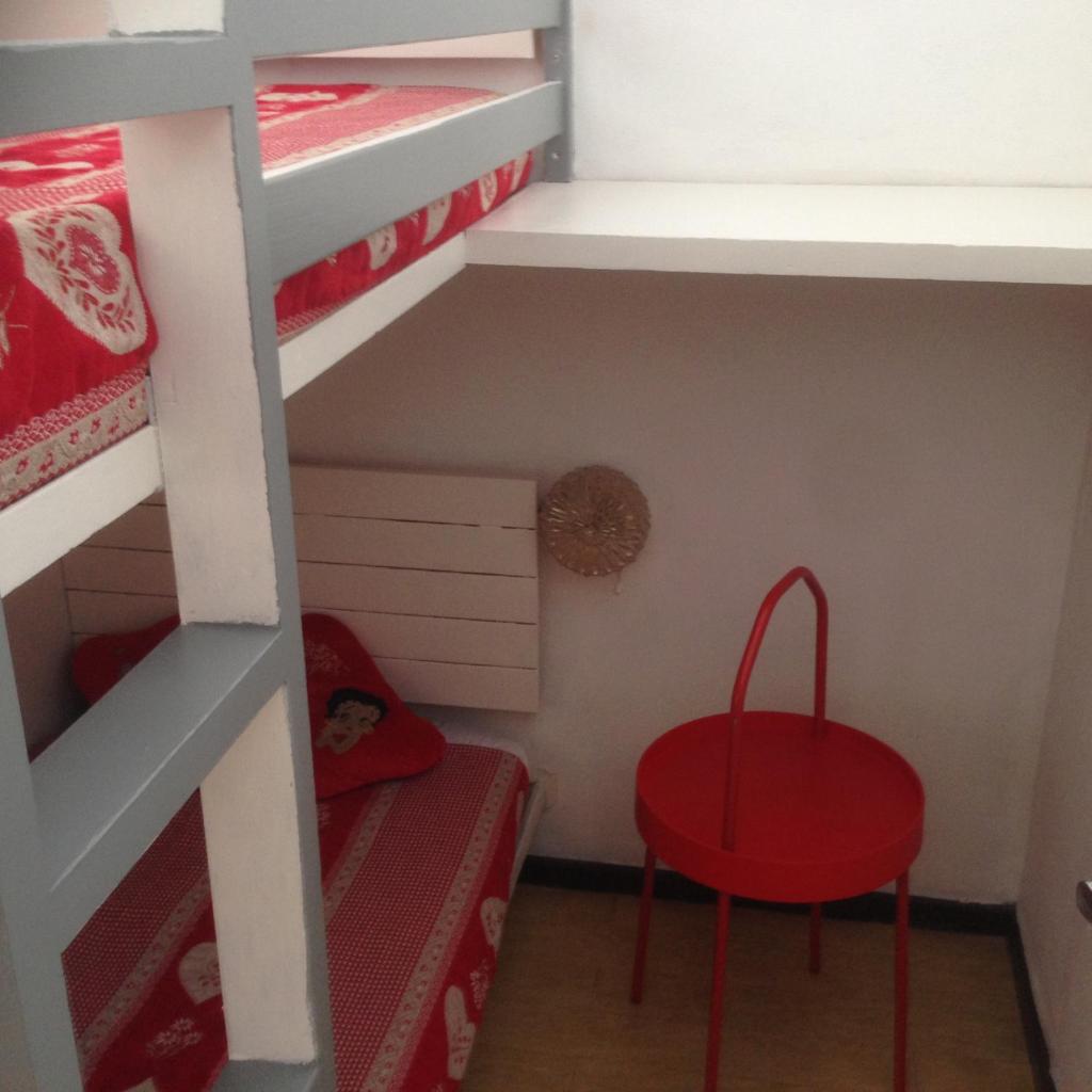 Cette petite chambre comprend un tabouret rouge et des lits superposés. dans l'établissement SuperDévoluy, Résidence le Bois D'Aurouze, à Saint-Étienne-en-Dévoluy