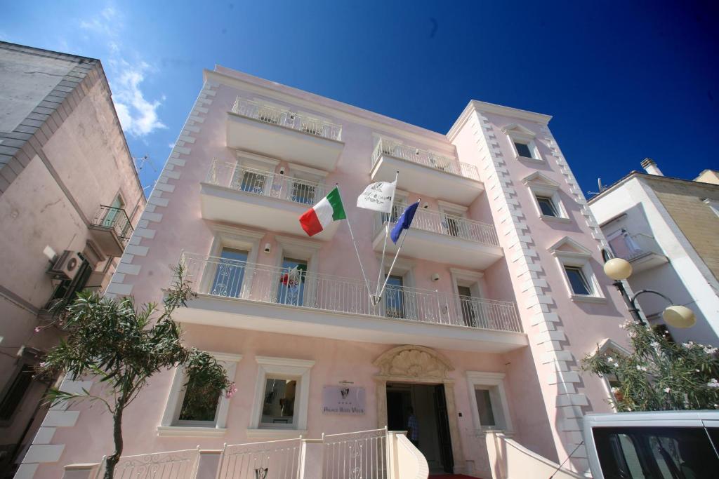 un grand bâtiment blanc avec deux drapeaux dessus dans l'établissement Palace Hotel Vieste, à Vieste 16 autres photos