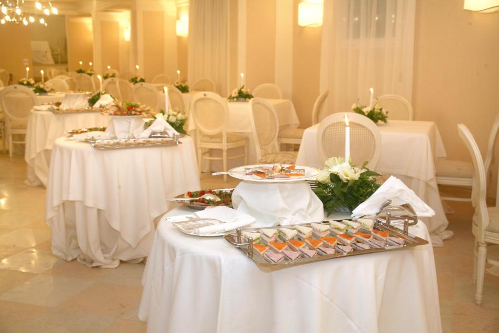 une salle à manger avec des tables blanches et des chaises blanches dans l'établissement Palace Hotel Vieste, à Vieste