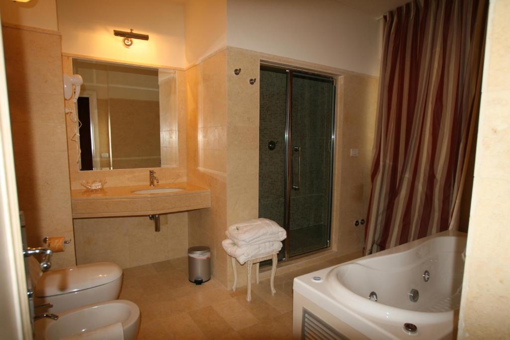 une salle de bains avec lavabo, baignoire et toilettes dans l'établissement Palace Hotel Vieste, à Vieste