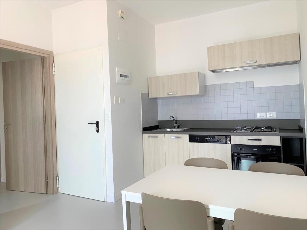 une cuisine blanche avec une table et des chaises blanches dans l'établissement Hotel & Residence Al Mare, à Lido di Jesolo