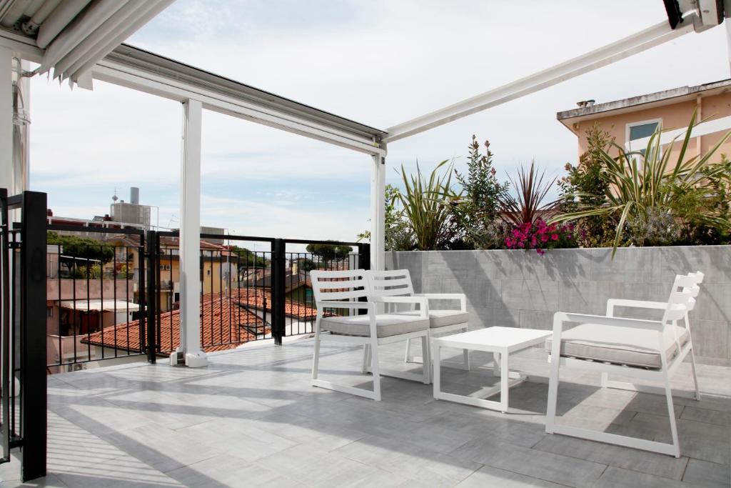 d'une terrasse avec des chaises et des tables blanches sur un balcon. dans l'établissement Meg Lifestyle Hotel & Apartaments, à Riccione