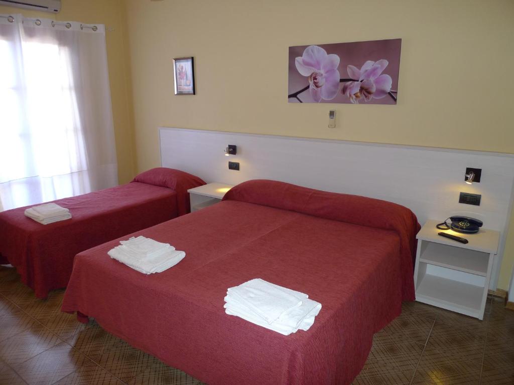 une chambre d'hôtel avec deux lits avec des draps rouges dans l'établissement Hotel Alexander, à Tropea