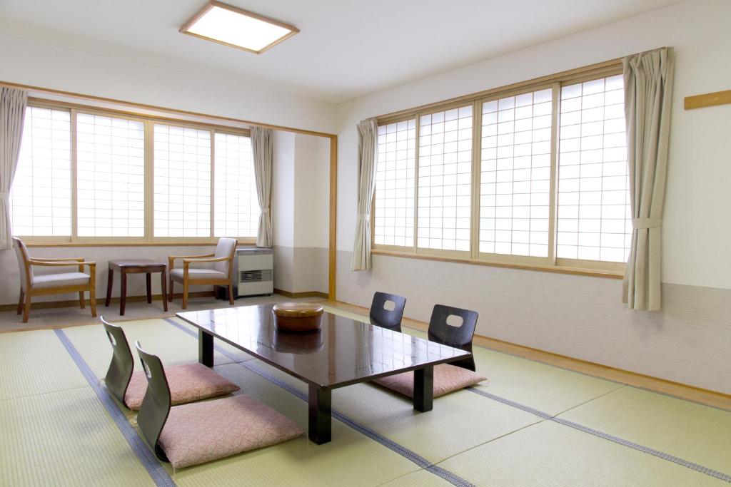 un salon avec une table, des chaises et des fenêtres dans l'établissement Hotel Yuzawa Yuzawa Denkiya, à Yuzawa