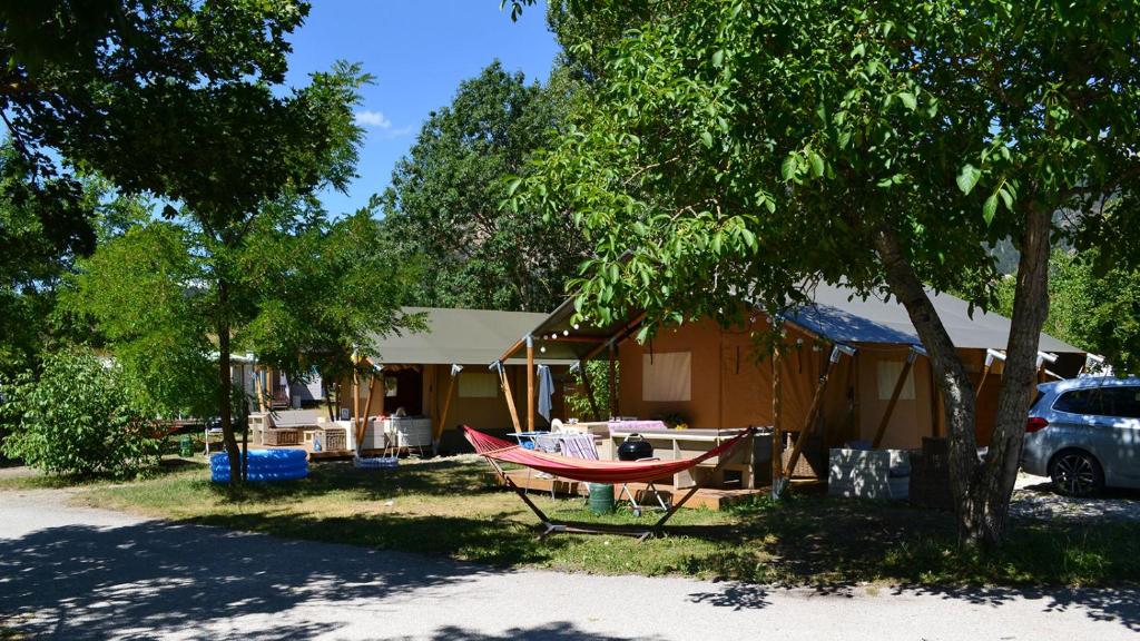 une maison avec un hamac en face de celle-ci dans l'établissement Glamping Villatent at Le Lac Bleu, à Châtillon-en-Diois