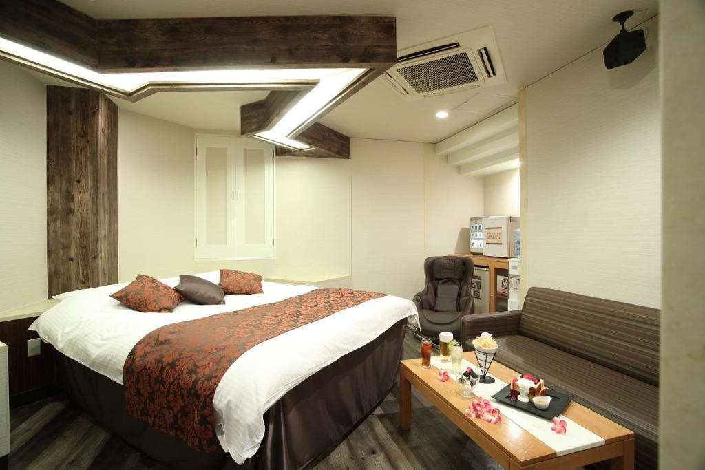 une chambre d'hôtel avec un lit et un canapé dans l'établissement ホテル ロコガーデン 小牧, à Toyoyama