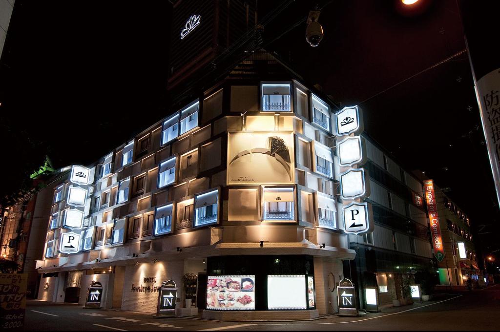 un bâtiment avec des panneaux sur son côté la nuit dans l'établissement ホテル ジュエリージュエリー 十三, à Osaka