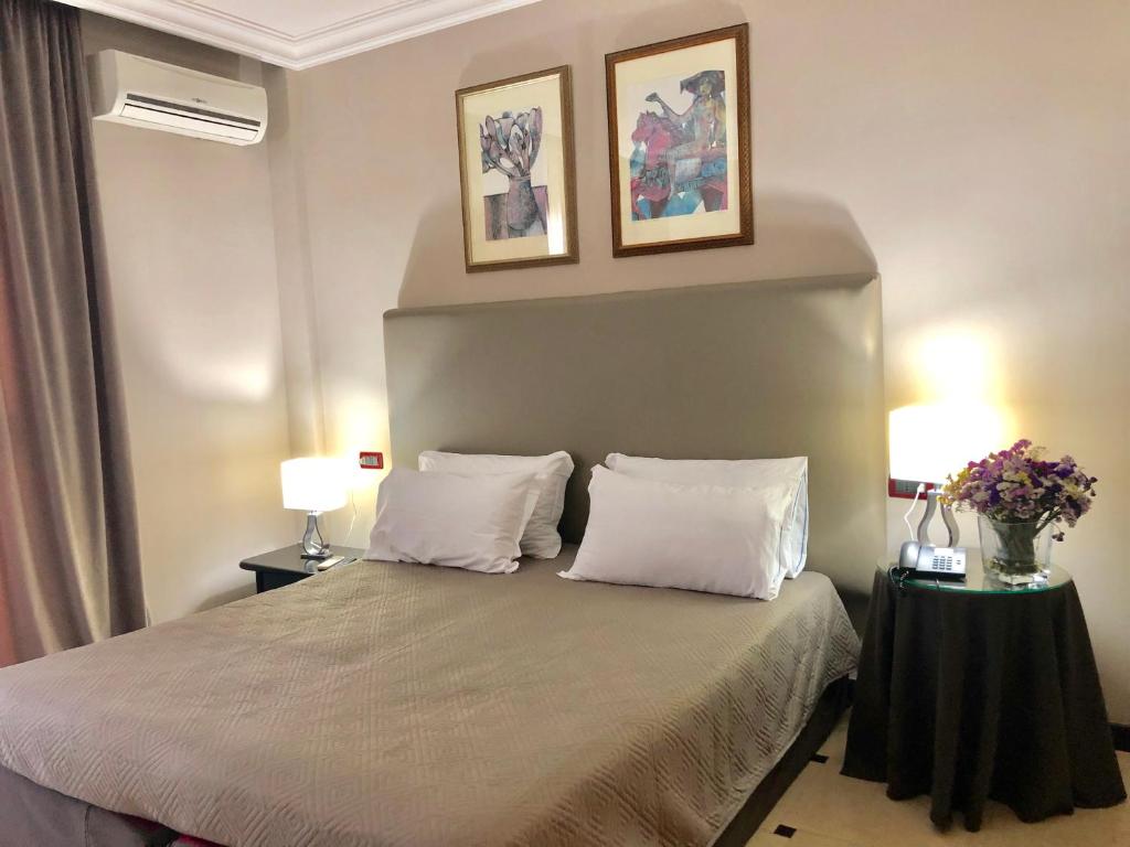une chambre avec un lit avec deux oreillers et deux tableaux dans l'établissement Domizia Palace Hotel, à Baia Domizia