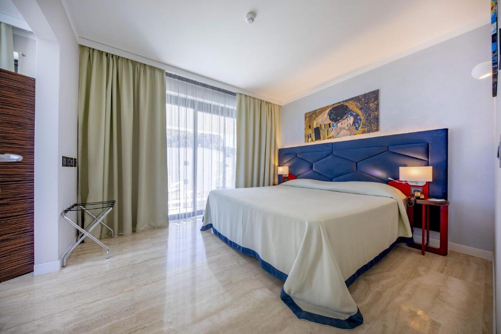 une chambre avec un grand lit et une grande fenêtre dans l'établissement Victoria Palace Cefalù, à Cefalù