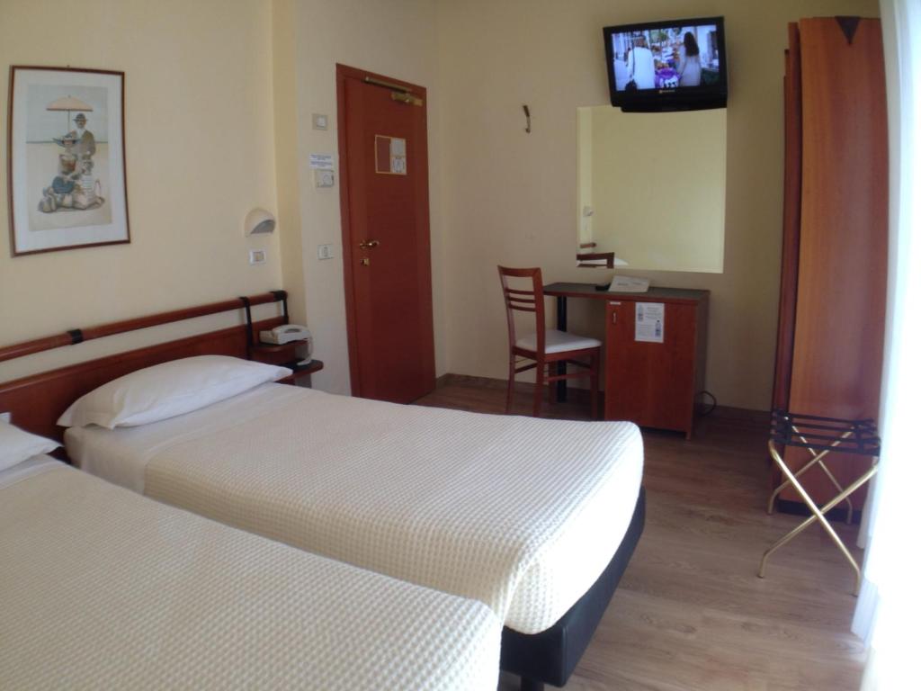 une chambre d'hôtel avec deux lits et une télévision dans l'établissement Hotel Houston, à Rimini