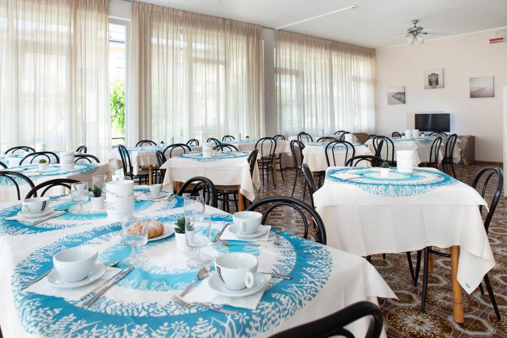 une salle de conférence avec des tables et du linge de maison bleu et blanc dans l'établissement Hotel Mara, à Rimini