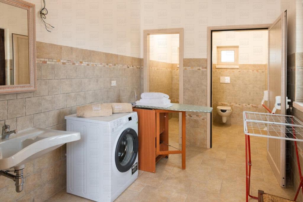 une salle de bain avec une machine à laver et un lavabo dans l'établissement HelloApulia - Masseria Petra Antica - Charming Family Retreat with Private Pool in Itria Valle, à Ceglie Messapica