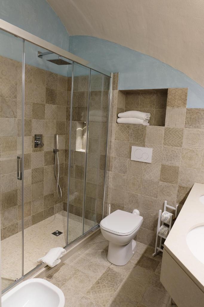 une salle de bain avec toilettes et douche en verre dans l'établissement Hotel Baia Di Puolo, à Massa Lubrense
