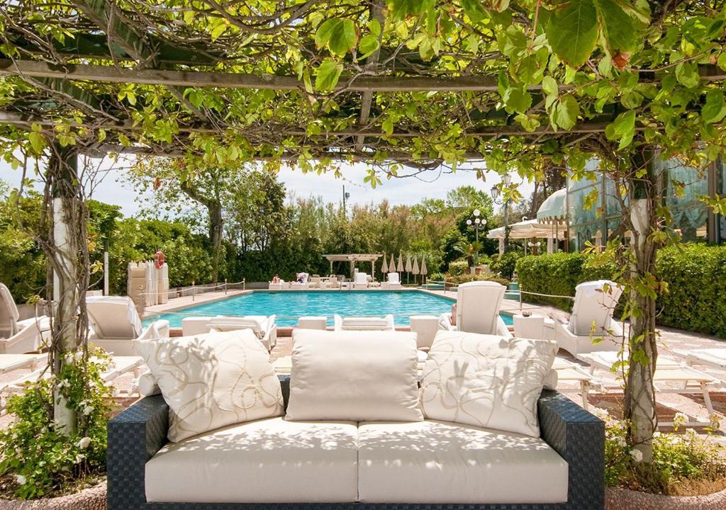 une pergola avec un canapé devant une piscine dans l'établissement Residenza Parco Fellini, à Rimini