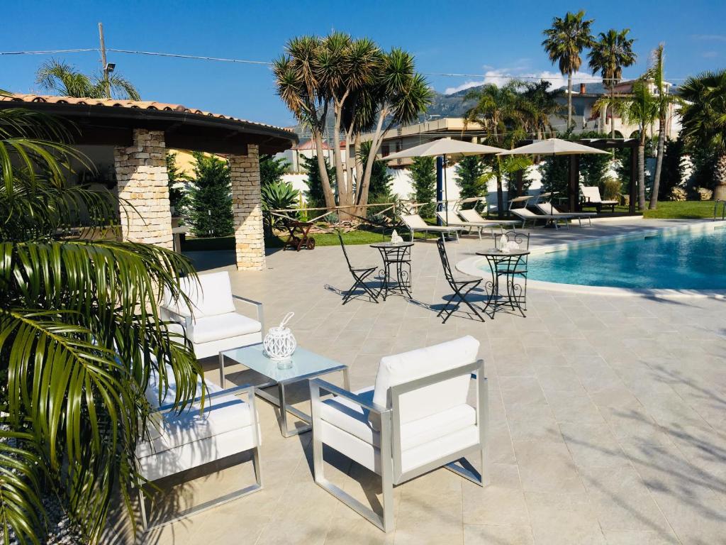 d'une terrasse avec des chaises et des tables à côté de la piscine. dans l'établissement Villa Araucaria, à Partinico