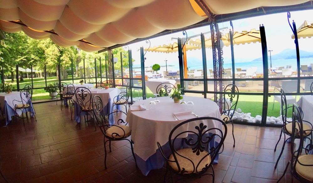 - un restaurant avec des tables et des chaises offrant une vue sur un champ dans l'établissement Hotel Lugana Parco Al Lago, à Sirmione