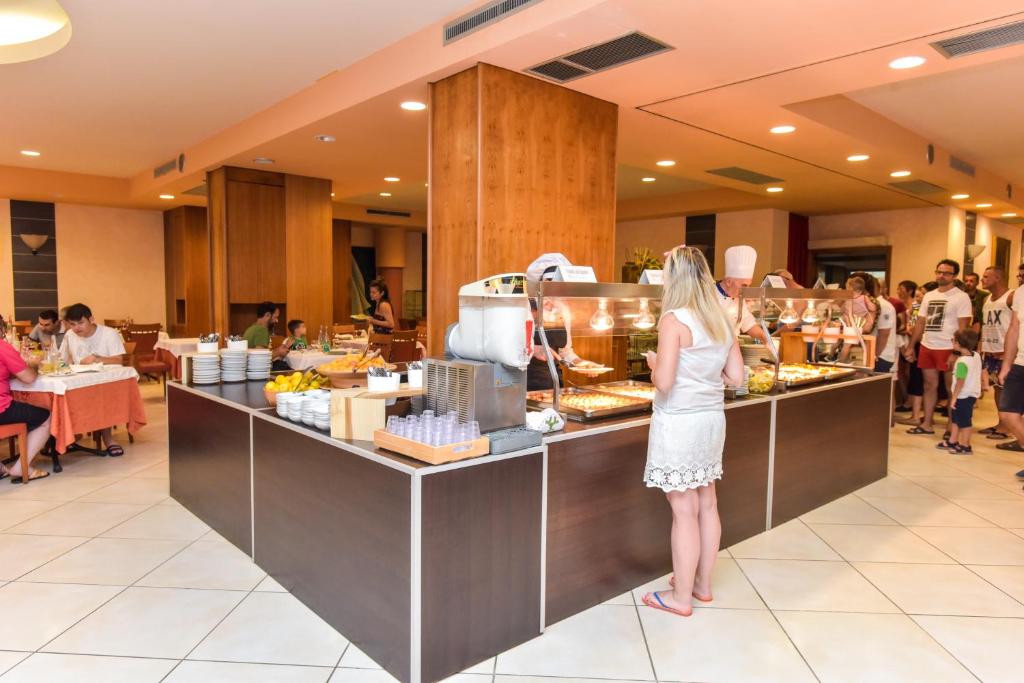 une femme préparant de la nourriture au comptoir d'un restaurant dans l'établissement Hotel Club Astor, à Ugento 38 autres photos