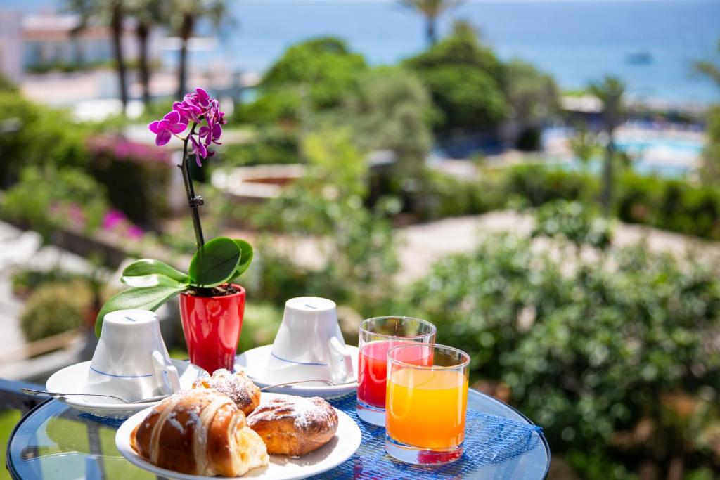une table avec une assiette de nourriture et deux verres de jus d'orange dans l'établissement Hotel La Mandorla, à Ischia