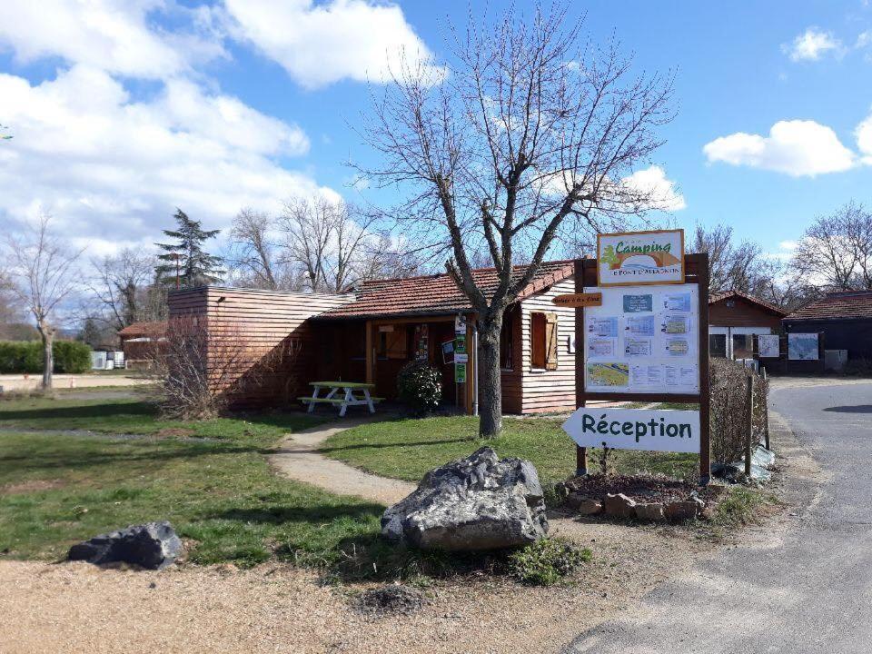 un panneau devant une cabane en rondins avec un panneau dans l'établissement Camping Le Pont d'Allagnon, à Lempdes-sur-Allagnon