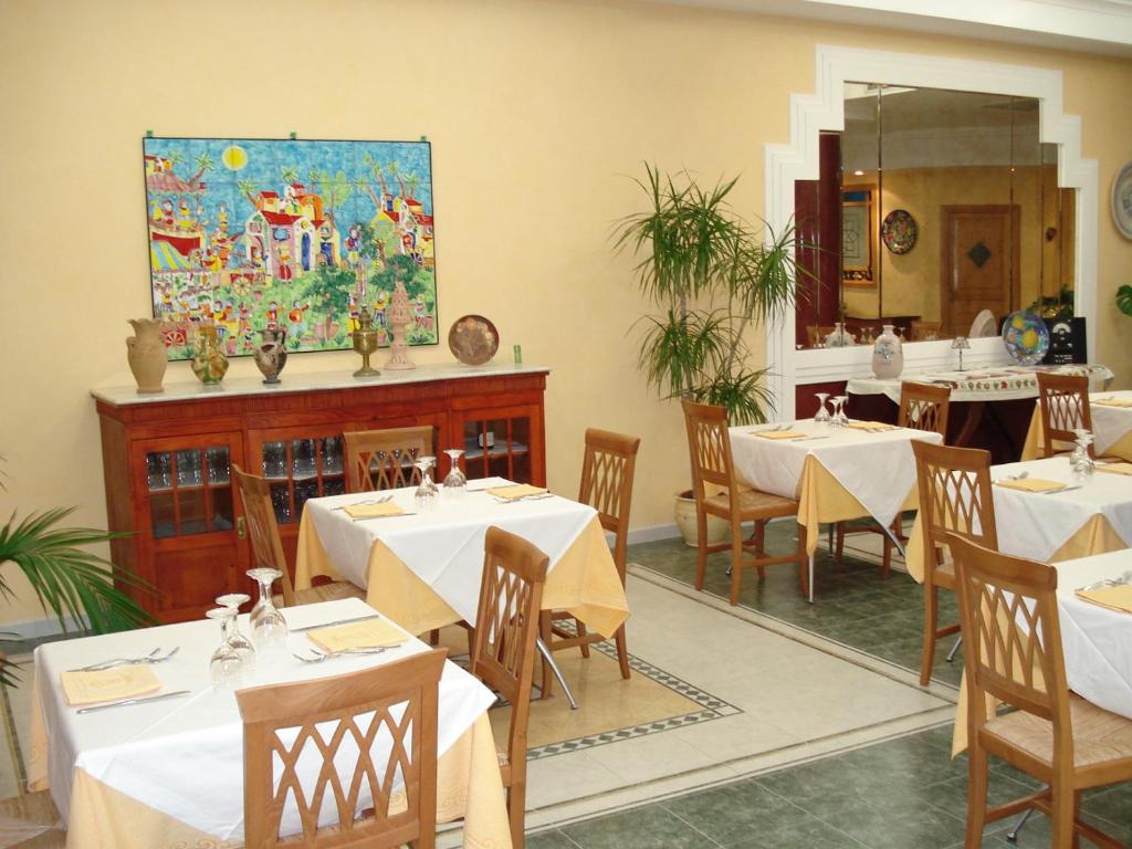 une salle à manger avec des tables et un tableau mural dans l'établissement Hotel Sicilya, à San Vito Lo Capo