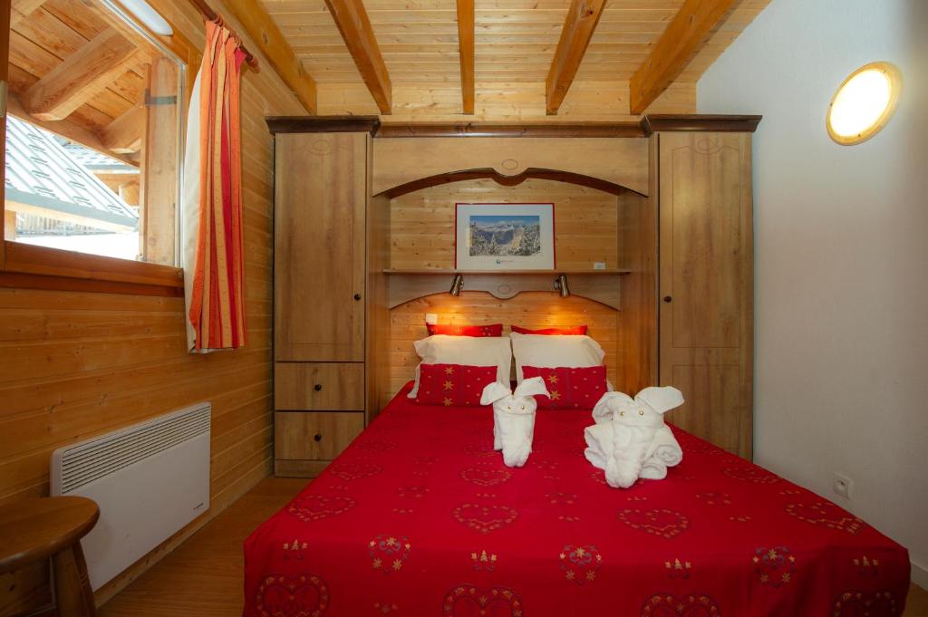 - une chambre dotée d'un lit rouge avec deux animaux rembourrés dans l'établissement Résidence Goélia Le Village Gaulois, à Saint-François-Longchamp