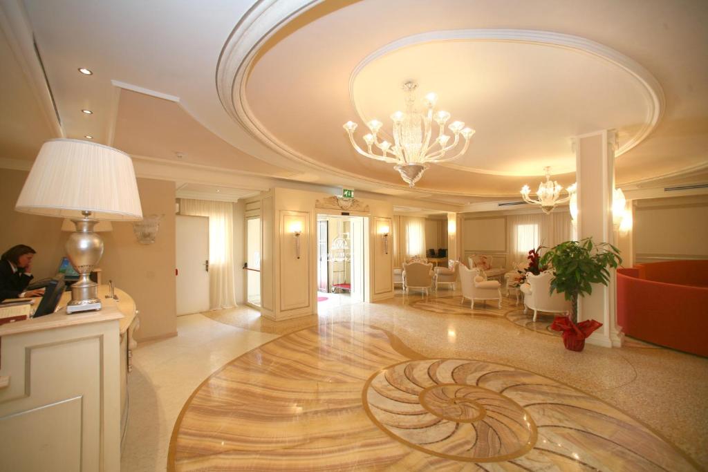un grand hall d'entrée avec un lustre et un parquet dans l'établissement Palace Hotel Vieste, à Vieste