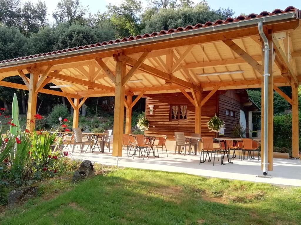 - un pavillon en bois avec des tables et des chaises dans la cour dans l'établissement LES PIERRES CHAUDES, à Veyrignac