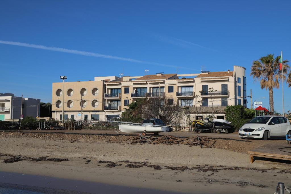 un grand bâtiment avec des voitures garées dans un parking dans l'établissement Hotel Celeste, à Marzamemi